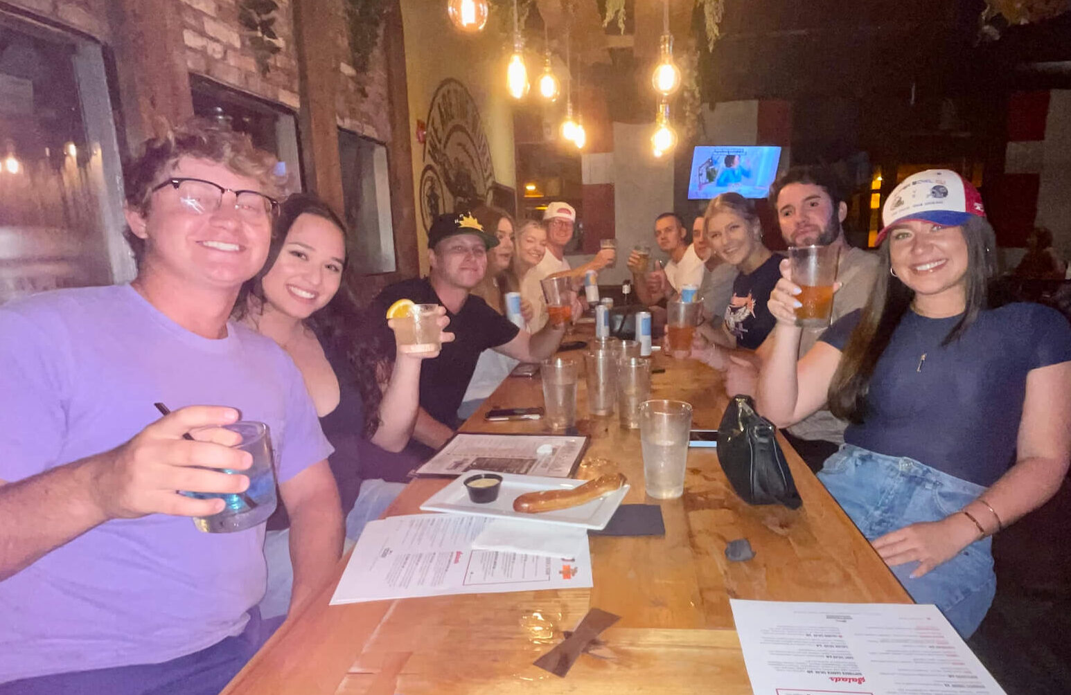 Hoptinger Bier Garden & Sausage House Jacksonville Beach FL 32250 trivia night group of young people smiling and raising their glasses