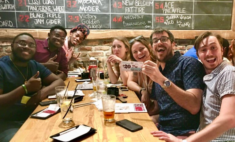 Hoptinger Bier Garden & Sausage House Jacksonville FL 32204 trivia night group of young people at a table with a chalkboard schedule behind them