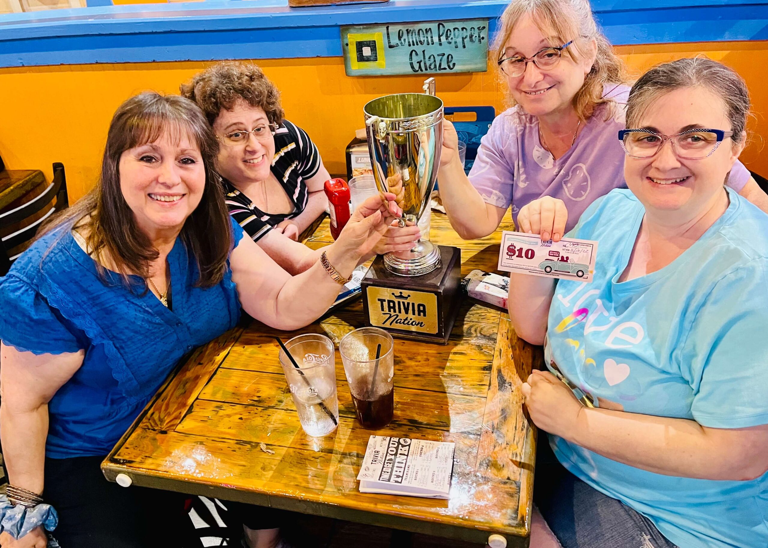 Hurricane Grill & Wings Coral Springs FL 33076 trivia night: group of four ladies seated around a table all smiling with a Trivia Nation trophy in between me and the woman in front holding up a $10 trivia coupon