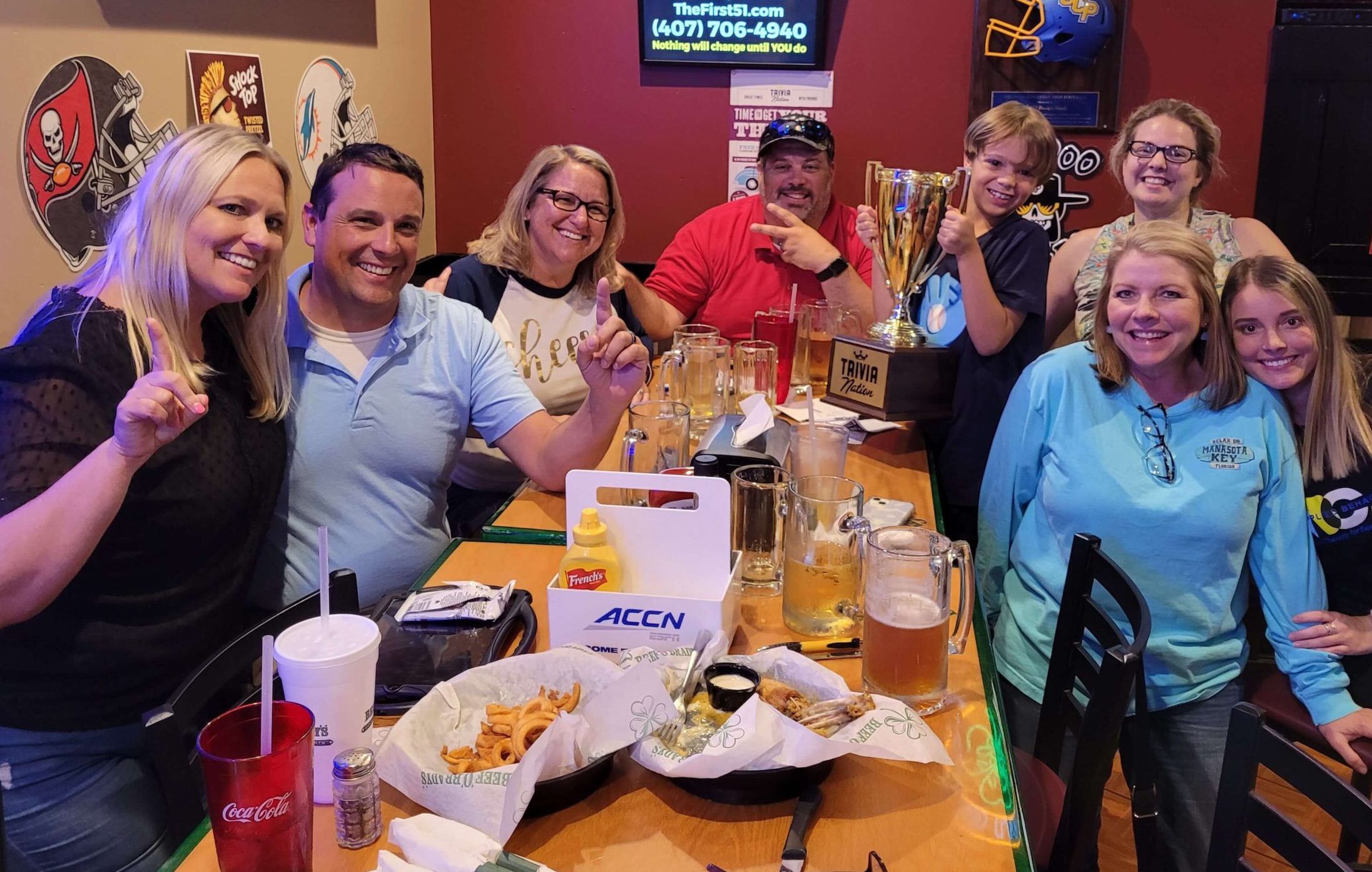 Beef O Brady's Oviedo FL 32765 trivia night: group of adults at a long table celebrating with beers and food as well as a child holding up a trophy